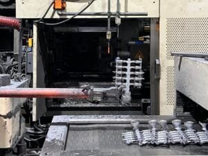 Molten aluminum being injected into a steel die casting mold inside a modern factory environment.