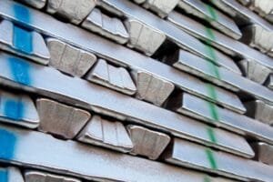 Stack of aluminum ingots on a pallet in a warehouse, ready to be melted as feedstock for aluminum die casting alloys.