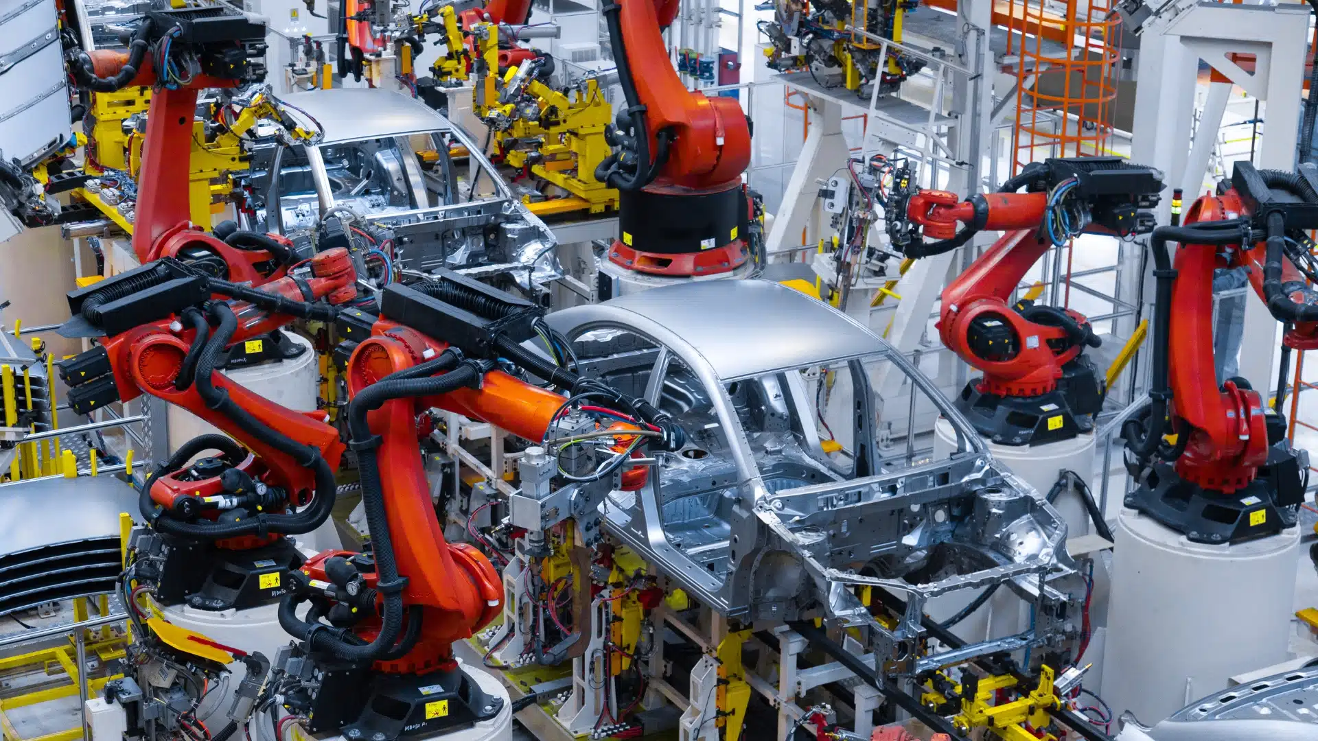Robotic arms assembling a car body-in-white on an automated automotive production line.