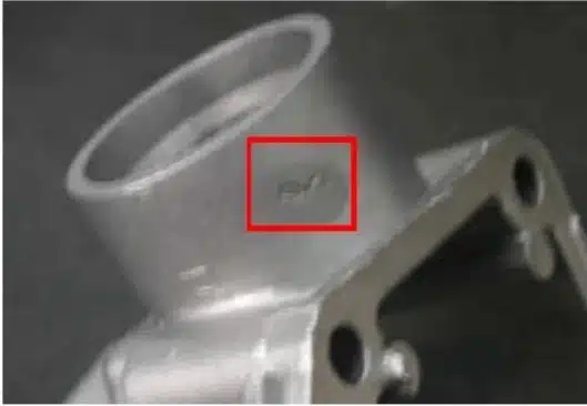 Aluminum die casting cold slug mark on boss wall—round/tadpole-shaped blemish.