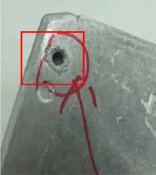 Open porosity/blowhole at corner of ADC12 die-cast part—void exposed on surface.