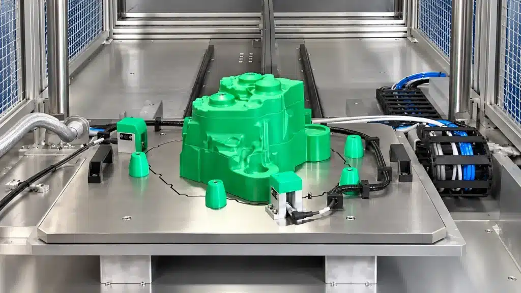 Die Casting Leak Testing: 3 Methods for Pressure-Tight Parts 5 Green housing mounted on a stainless steel test fixture with sensors, positioning caps, and cables.
