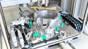 Silver metal casting held in an industrial test fixture with clamps, sensors, and blue cables.