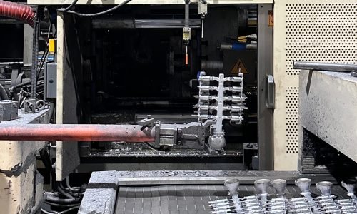 Molten aluminum being injected into a steel die casting mold inside a modern factory environment.