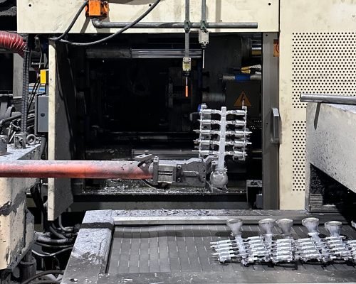 Molten aluminum being injected into a steel die casting mold inside a modern factory environment.